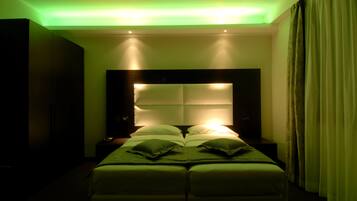A hotel room with a large bed, a headboard with illuminated panels, and a nightstand with a lamp.
