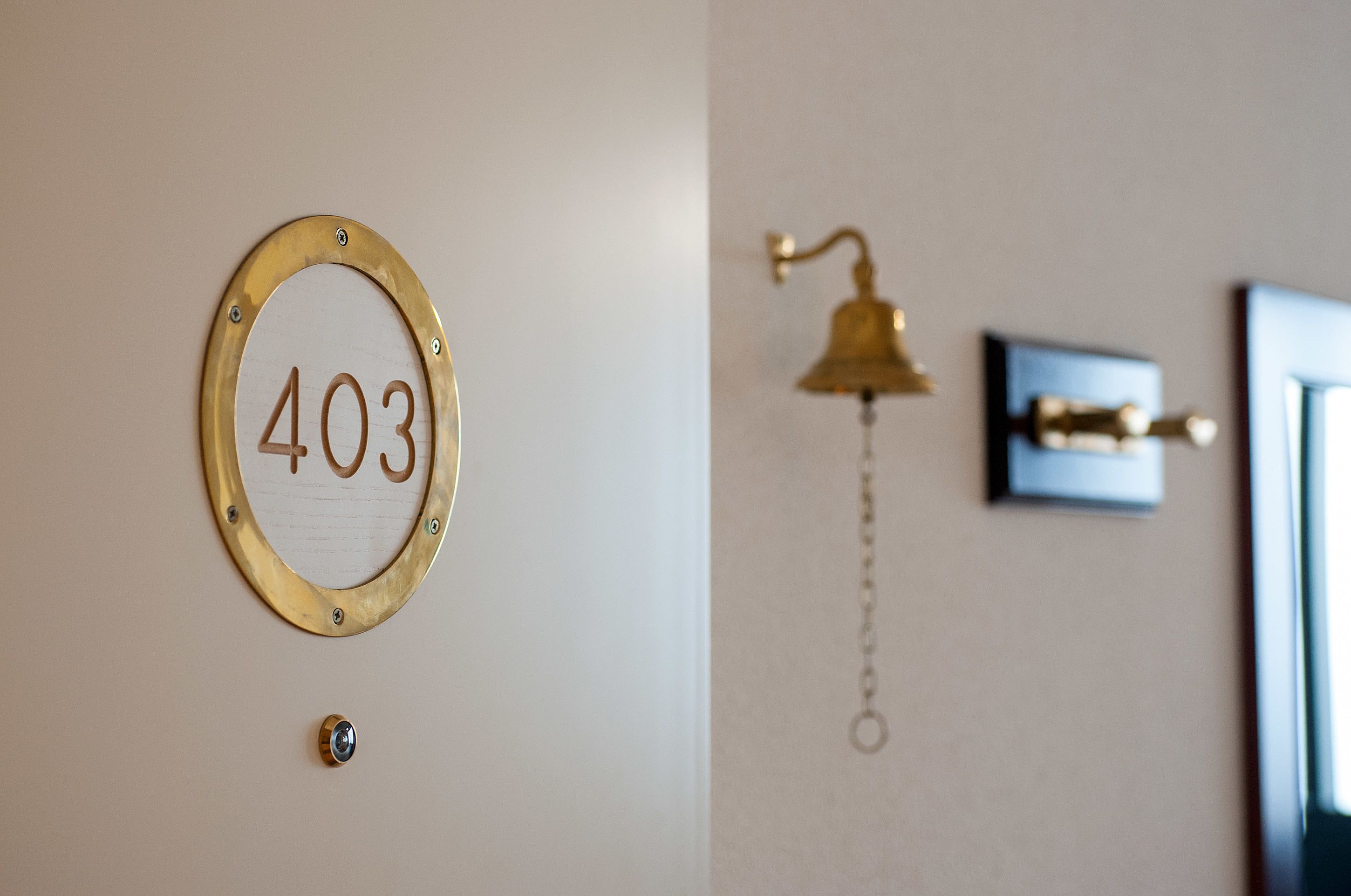 Egy szoba, amelyen egy sárgaréz tábla található, rajta a „403” szám, és a falon egy sárgarézből készült harang.