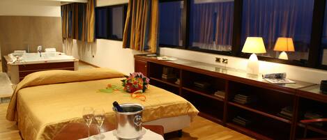 Une chambre d’hôtel avec un lit, une table de chevet et un bureau avec une lampe.