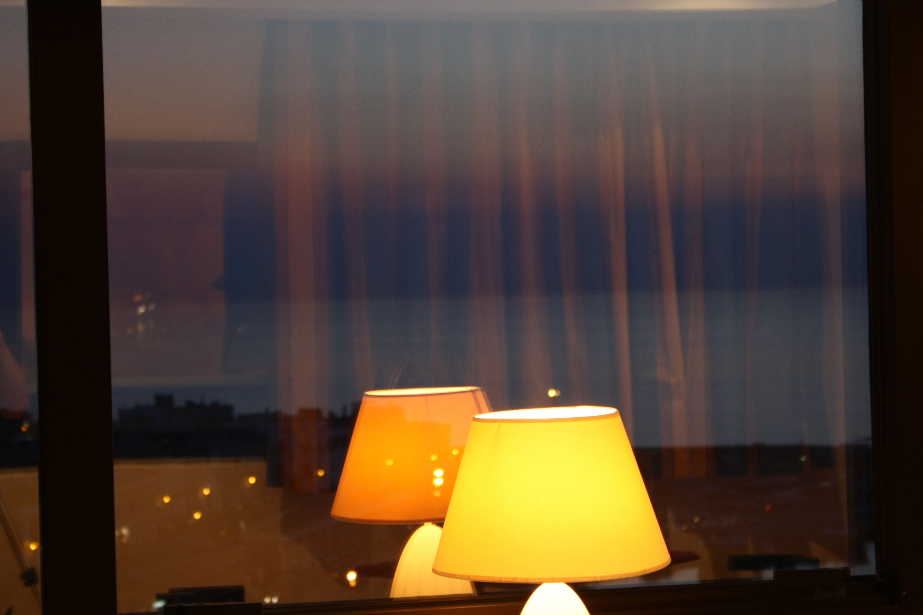 Una ventana con dos lámparas y vistas a edificios.