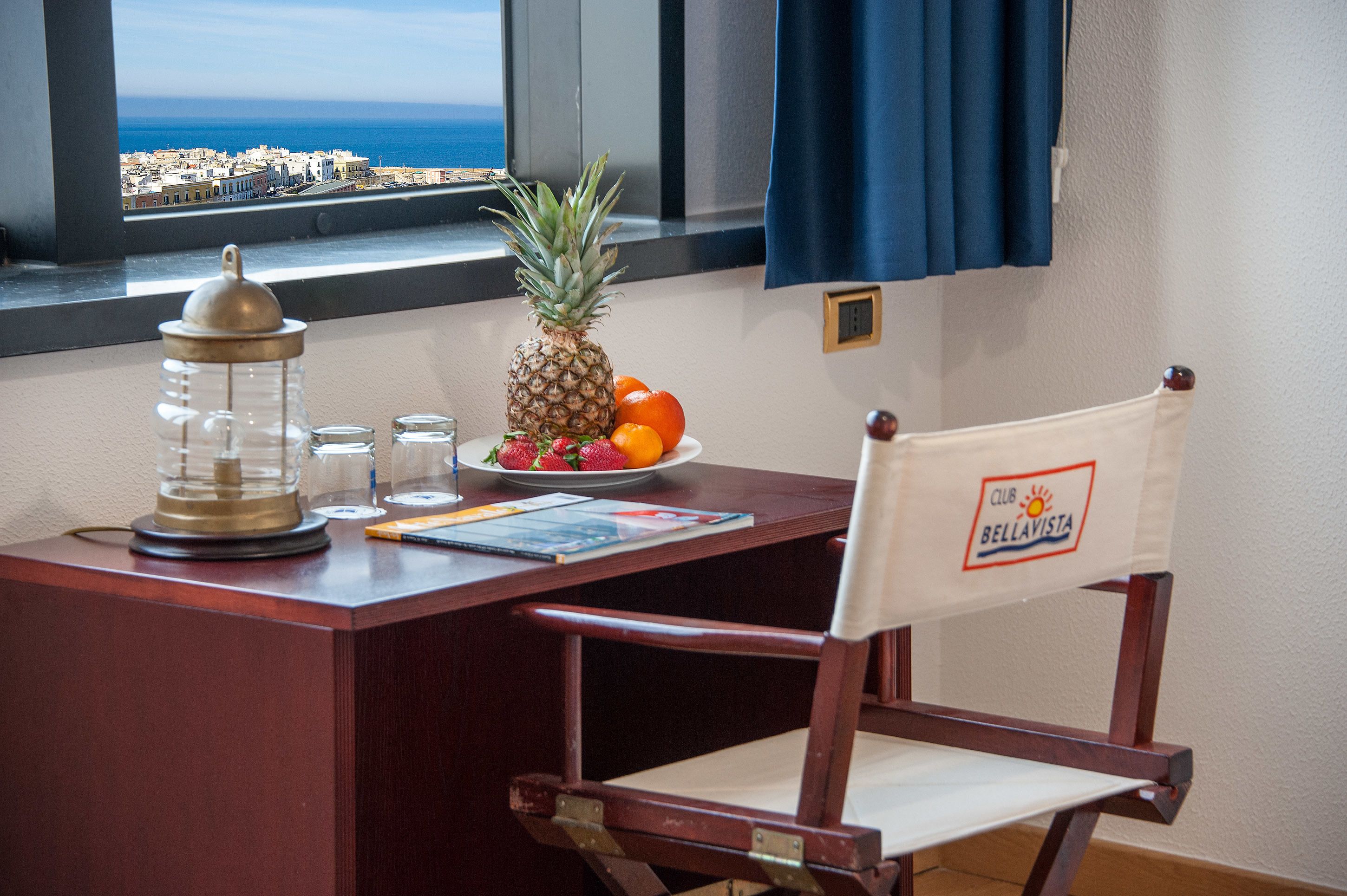 Een houten bureau met uitzicht op de stad, een ananas, sinaasappels en een glazen pot.