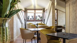 Un espace repas avec des tables et des chaises, une grande fenêtre et une plante dans un vase.