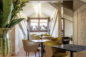 A dining area with tables and chairs, a large window, and a plant in a vase. - Ca' Del Campo (Venice)