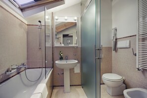 Un baño moderno con bañera, lavamanos, inodoro y cabina de ducha con paredes de vidrio.