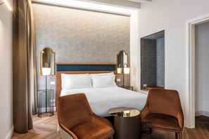 A hotel room with a large bed, two armchairs, a round table, and two wall-mounted lamps. - Ca' Del Campo (Venice)
