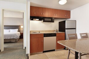 Una habitación de hotel compacta con kitchenette, una cama y un comedor.