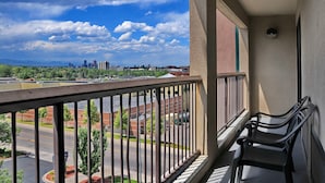 A balcony with a view of a cityscape, a parking lot, and a building with a red roof. - Hampton Inn & Suites Denver - Cherry Creek (Glendale)