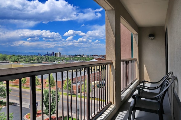 A balcony with a view of a cityscape, a parking lot, and a building with a red roof.