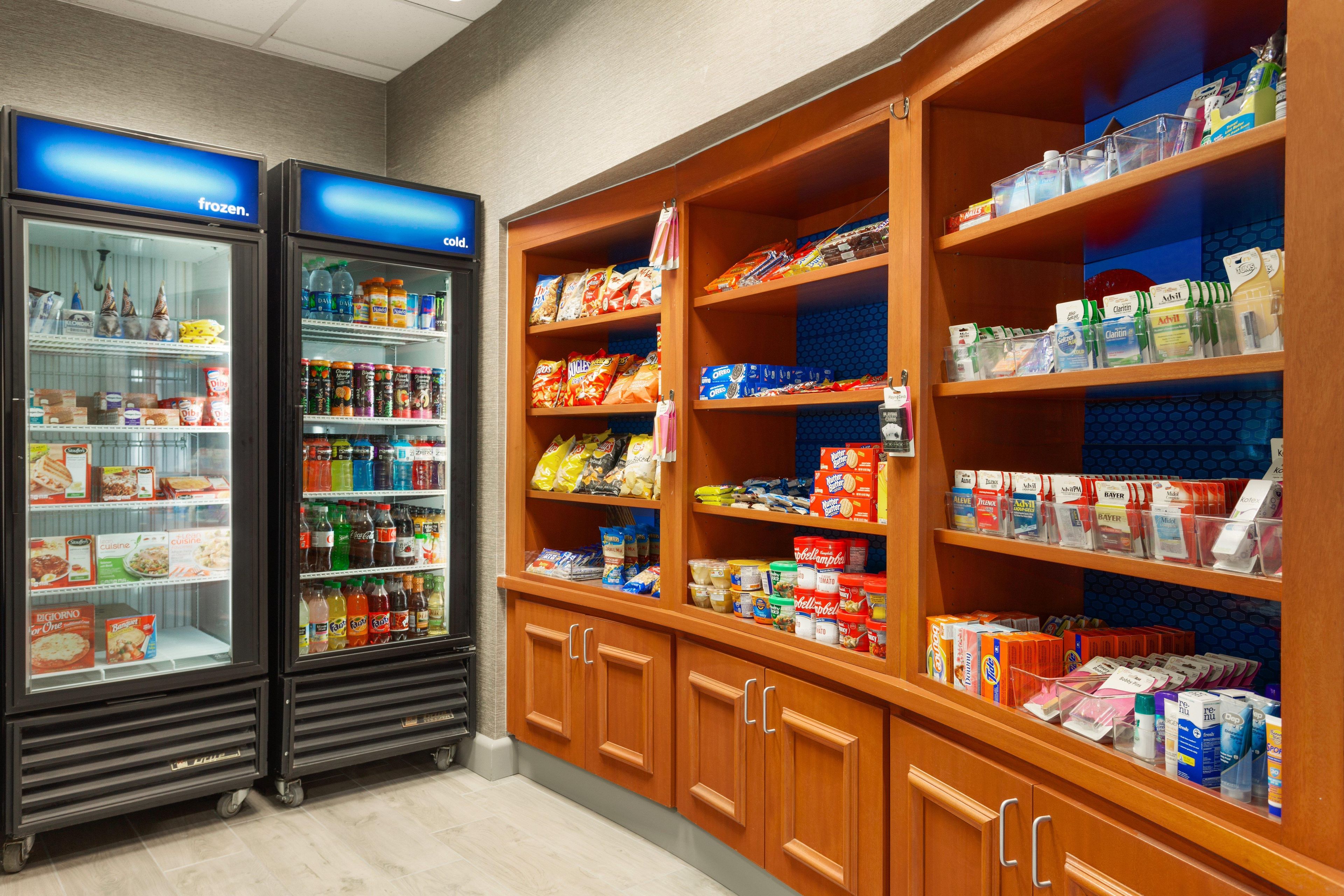 A refrigerated display case with various beverages and a shelf stocked with snacks and packaged goods.