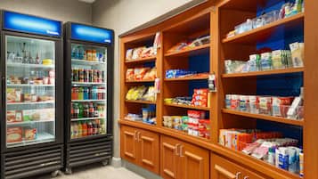 A refrigerated display case with various beverages and a shelf stocked with snacks and packaged goods.