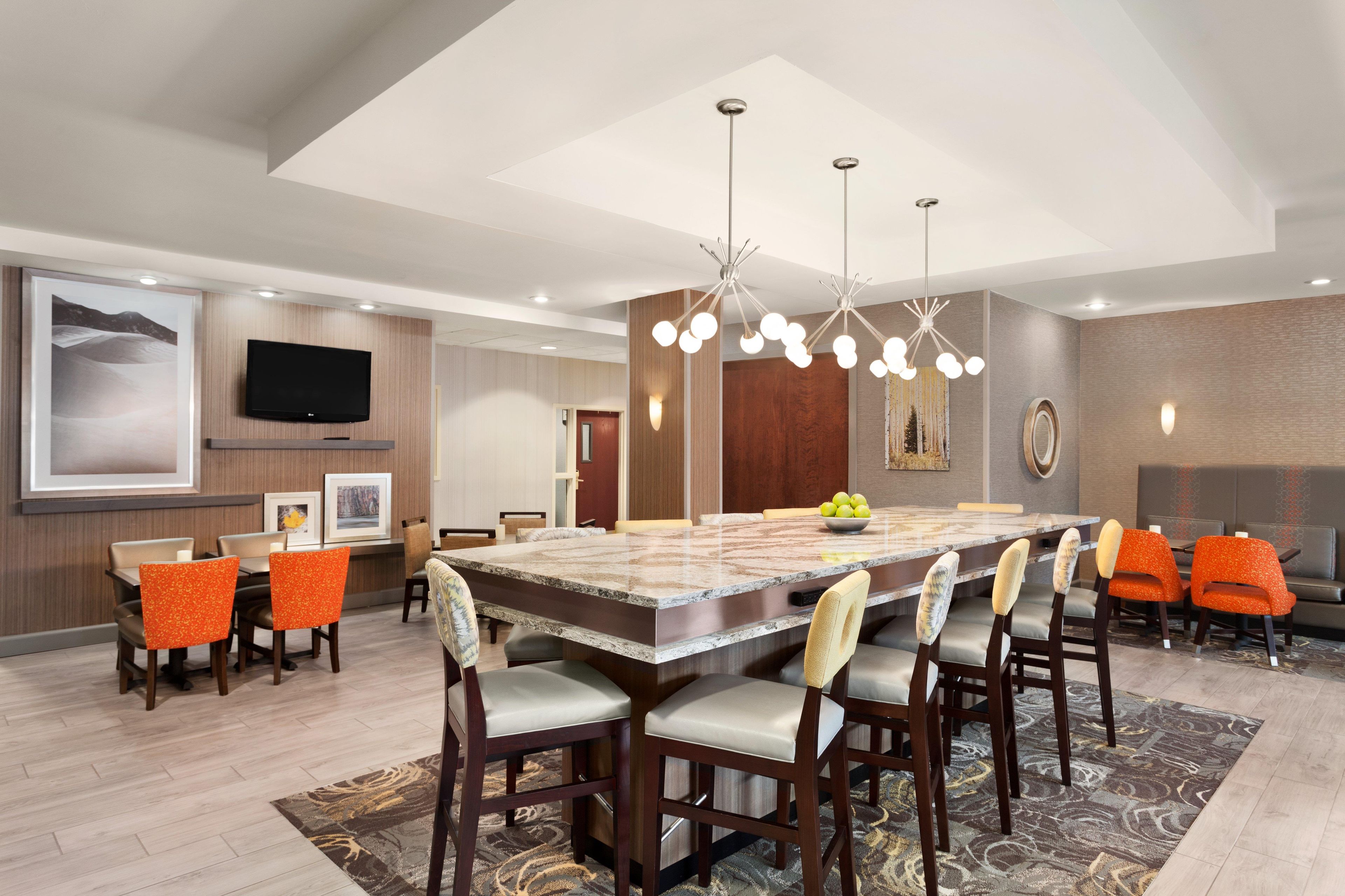 A modern dining area with a large marble table, multiple chairs, and a chandelier.