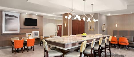 A modern dining area with a large marble table, multiple chairs, and a chandelier.