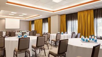 A conference room with round tables, chairs, and water bottles.