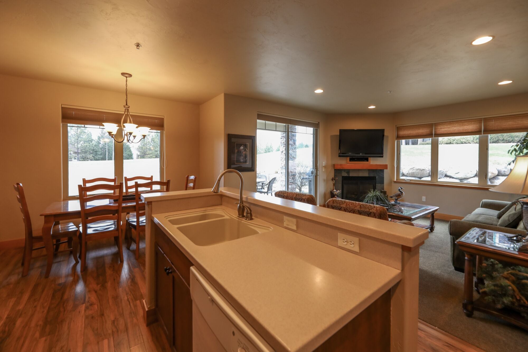 A kitchen with a large island, dining area with chairs, a fireplace, and a TV mounted on the wall.