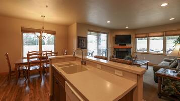 A kitchen with a large island, dining area with chairs, a fireplace, and a TV mounted on the wall.