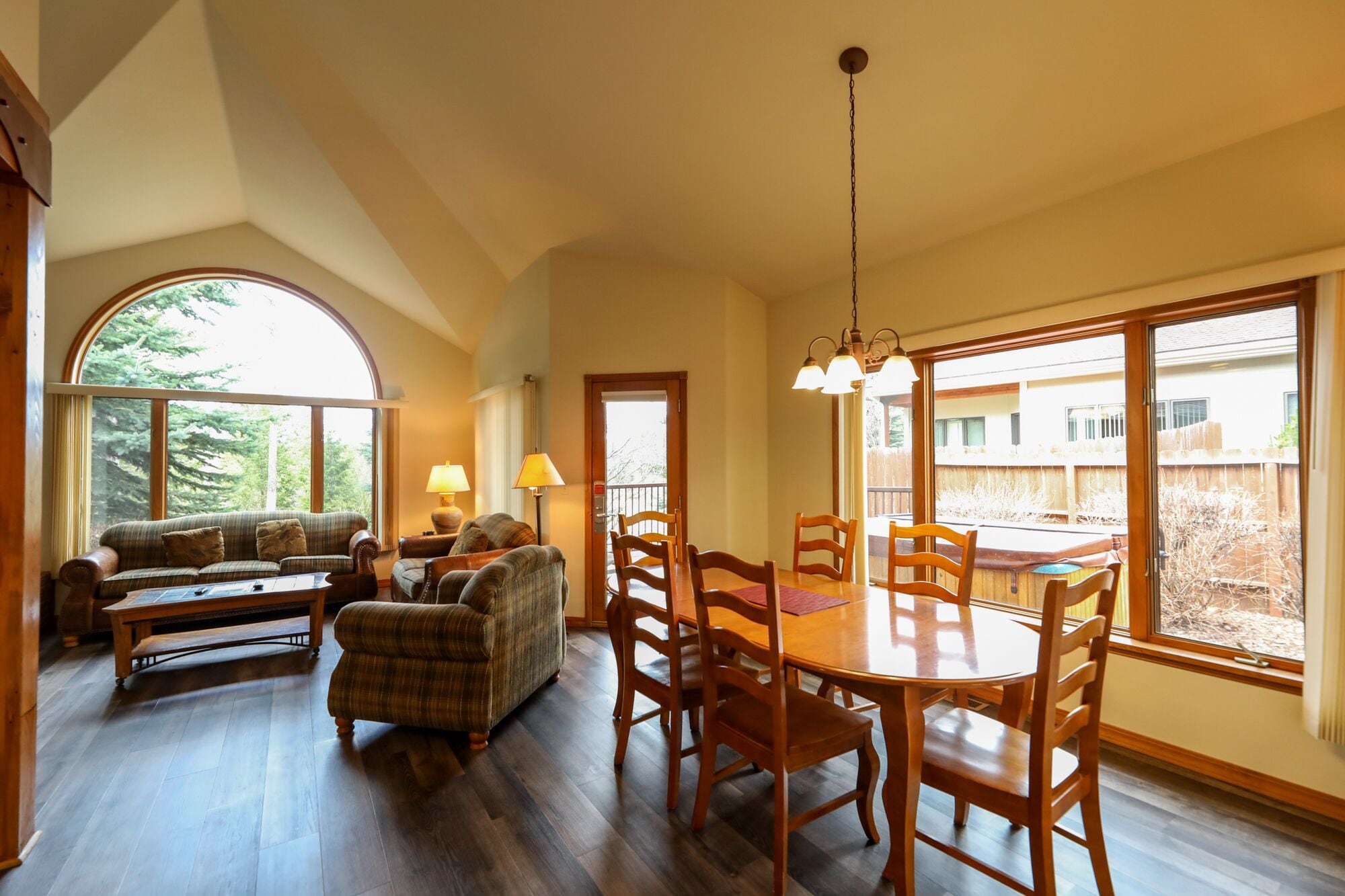 A spacious dining area with a wooden table and chairs, a sofa, and a lamp.