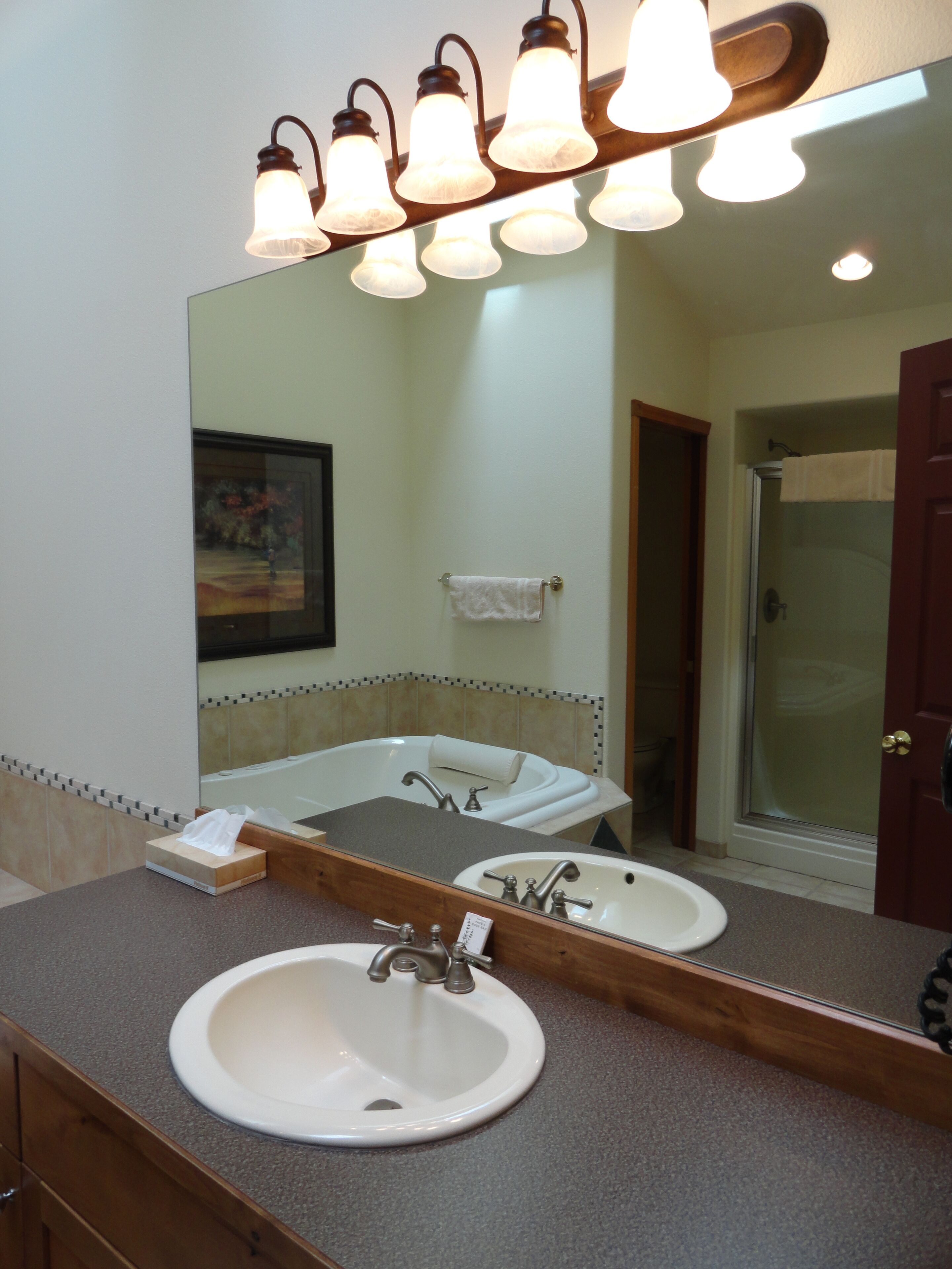 A bathroom with a large mirror, two sinks, a bathtub, and a shower.