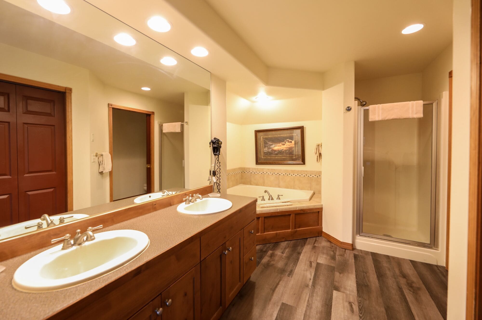 Une salle de bain avec deux lavabos, une douche et un grand miroir.
