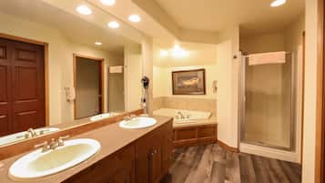 A bathroom with two sinks, a shower, and a large mirror.