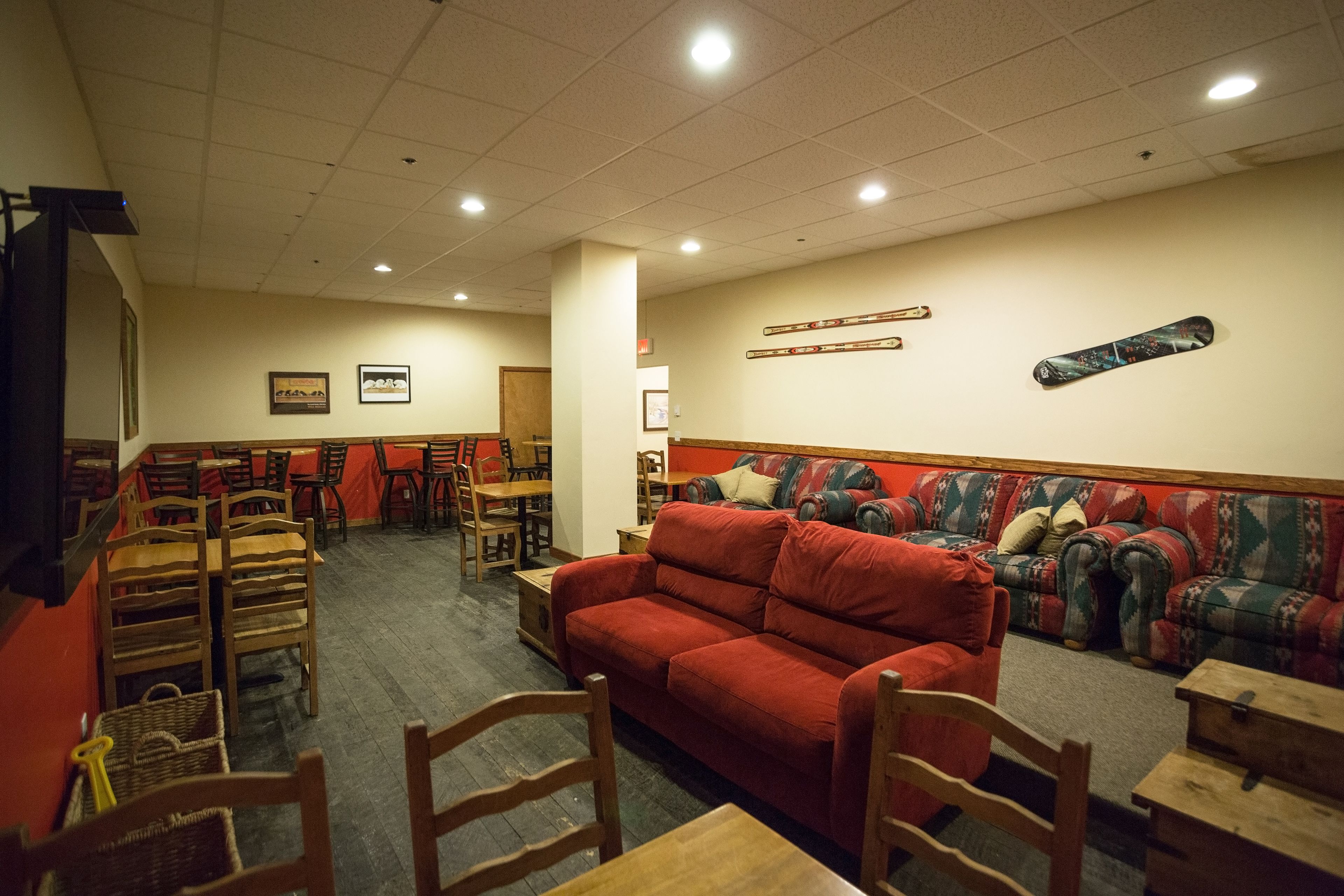 Un restaurante con mesas y sillas de madera, un sofá rojo y un sofá estampado.