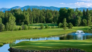 A golf course with a pond, trees, and mountains in the background. - Meadow Lake Resort & Condos (Columbia Falls)
