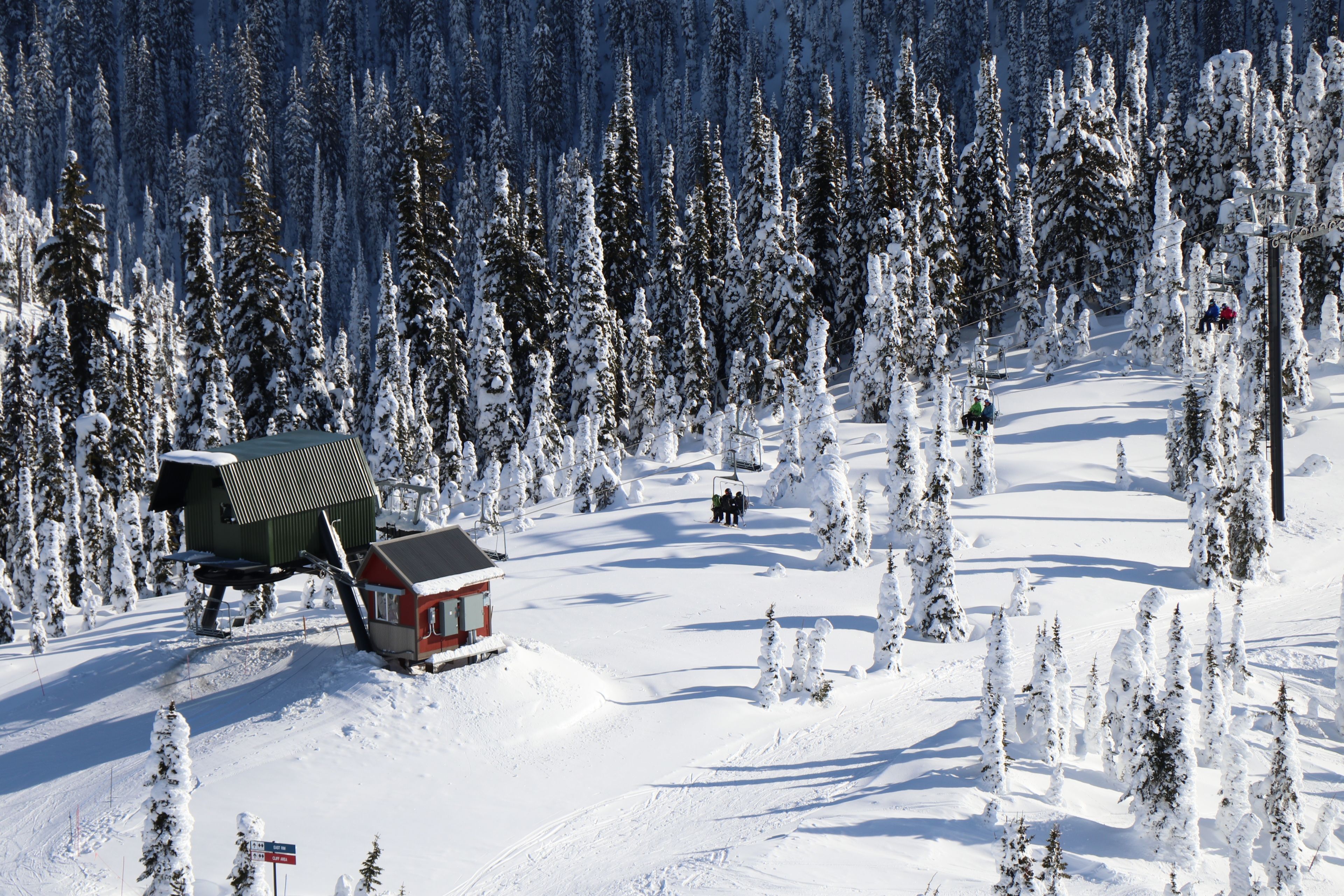 A ski resort with a chairlift, snow-covered trees, and a small lodge.