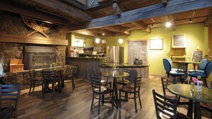 A rustic interior with stone walls, wooden beams, a fireplace, and a bar area with seating. - Meadow Lake Resort & Condos (Columbia Falls)