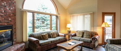 A cozy living room with a fireplace, two sofas, a coffee table, and a lamp.