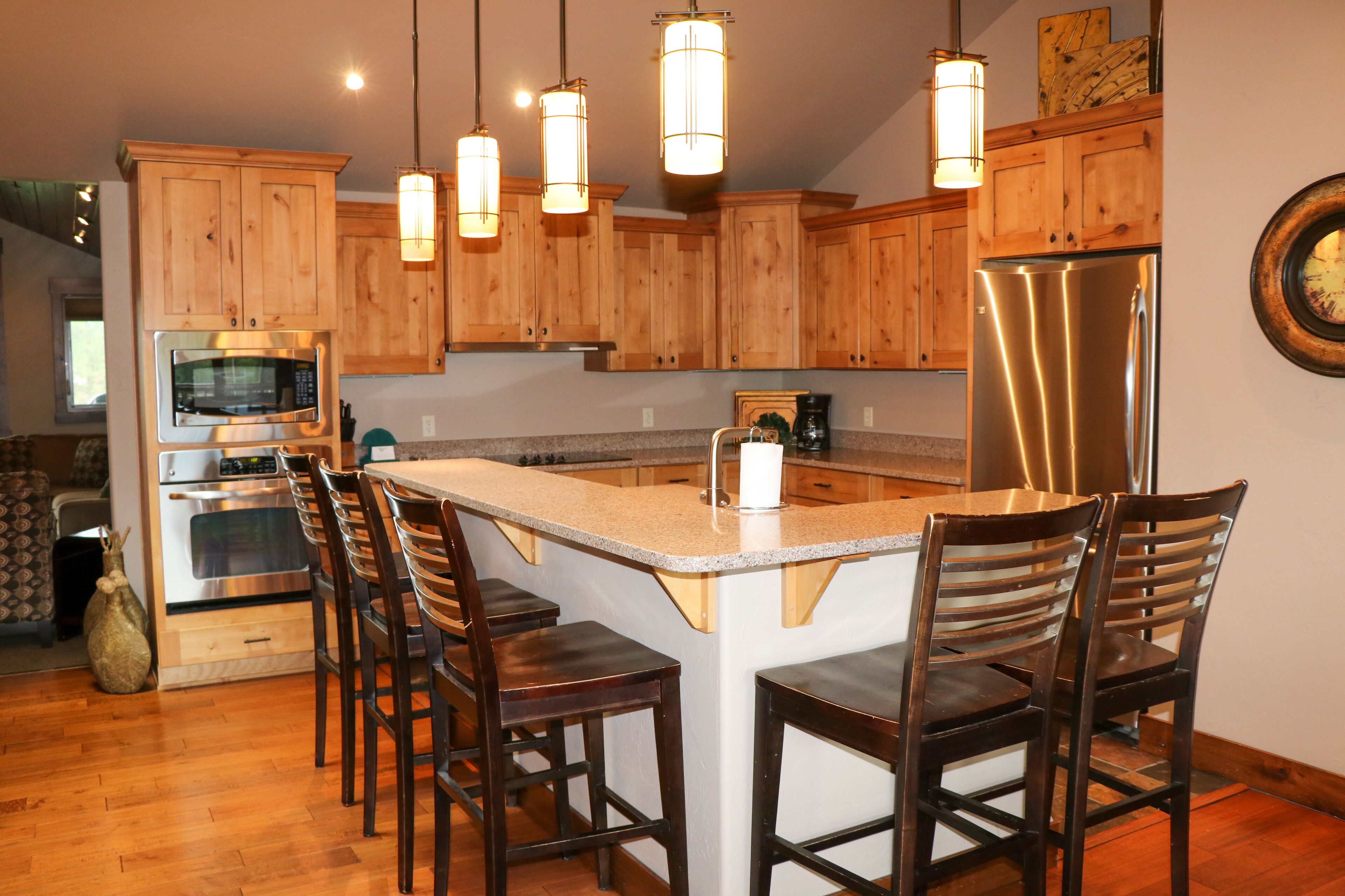 A kitchen with wooden cabinets, stainless steel appliances, and a central island with bar stools.