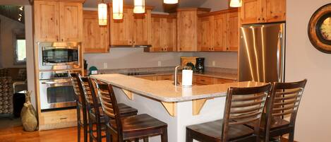 A kitchen with wooden cabinets, stainless steel appliances, and a central island with bar stools.