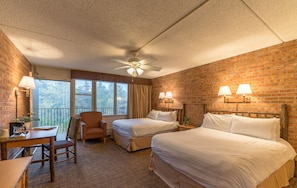 A hotel room with two beds, a desk, a chair, a ceiling fan, and a view of the outdoors. - Mountain Chalet Snowmass (Snowmass Village)