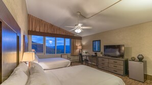 Habitación de hotel con dos camas, un escritorio, un televisor y vistas a la montaña.