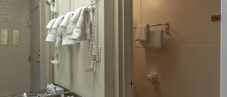 A bathroom with a sink, mirror, towel rack, and a hairdryer plugged in.