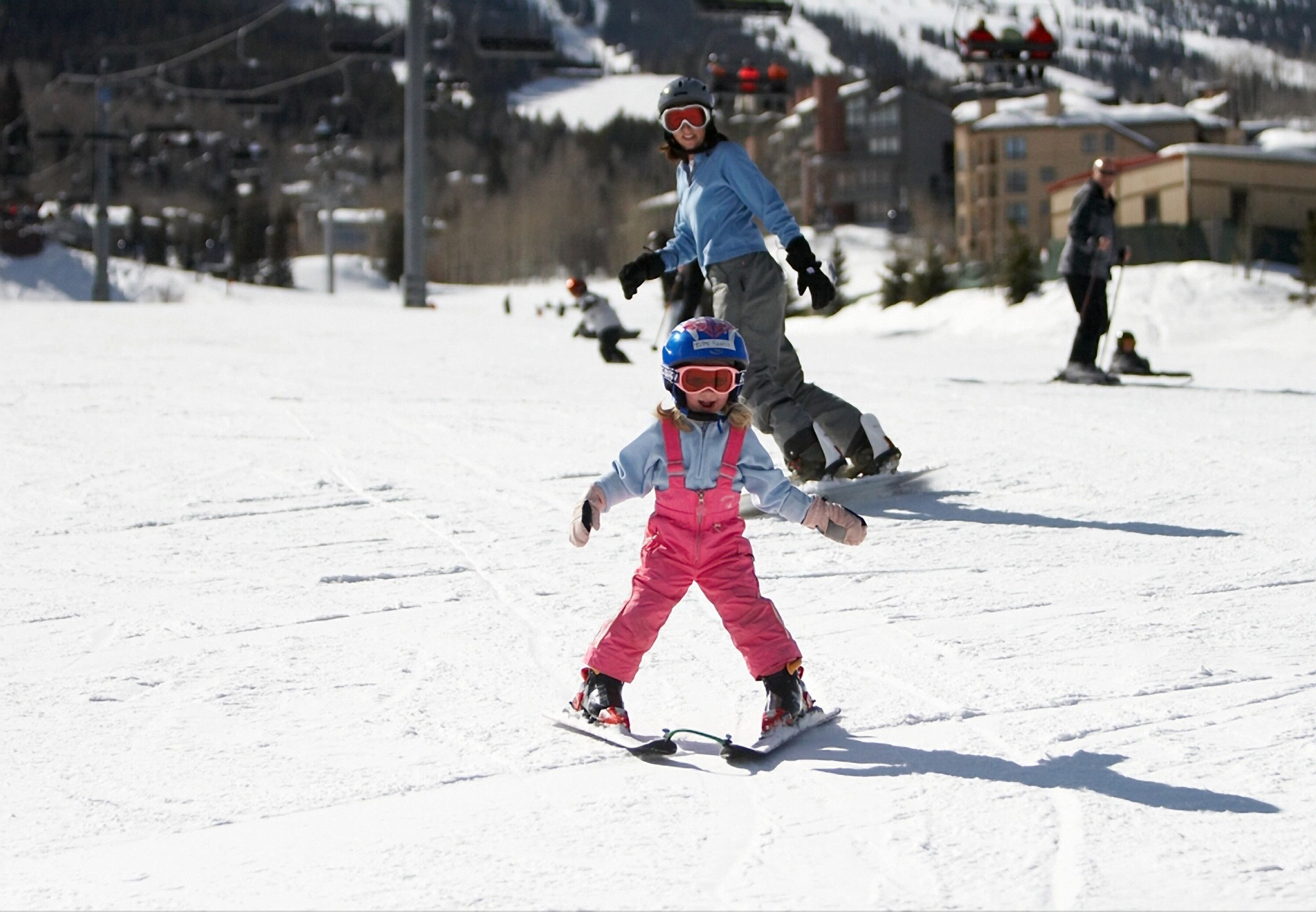 A ski slope with skiers and a child in pink ski gear.