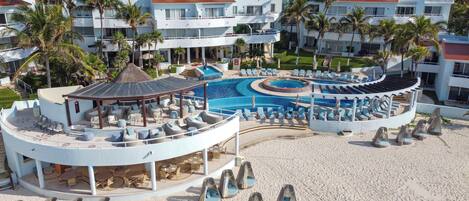 Un resort con una piscina grande, sillas de descanso y una zona de estar techada.