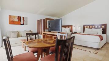 Una habitación de hotel con cama, televisión, zona de comedor con sillas y mesa, y un sofá.