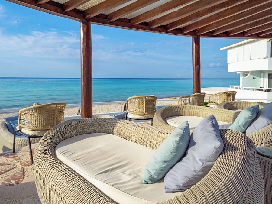 A beachside lounge with wicker furniture and a view of the ocean.