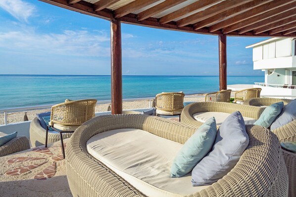 A beachside lounge with wicker furniture and a view of the ocean.