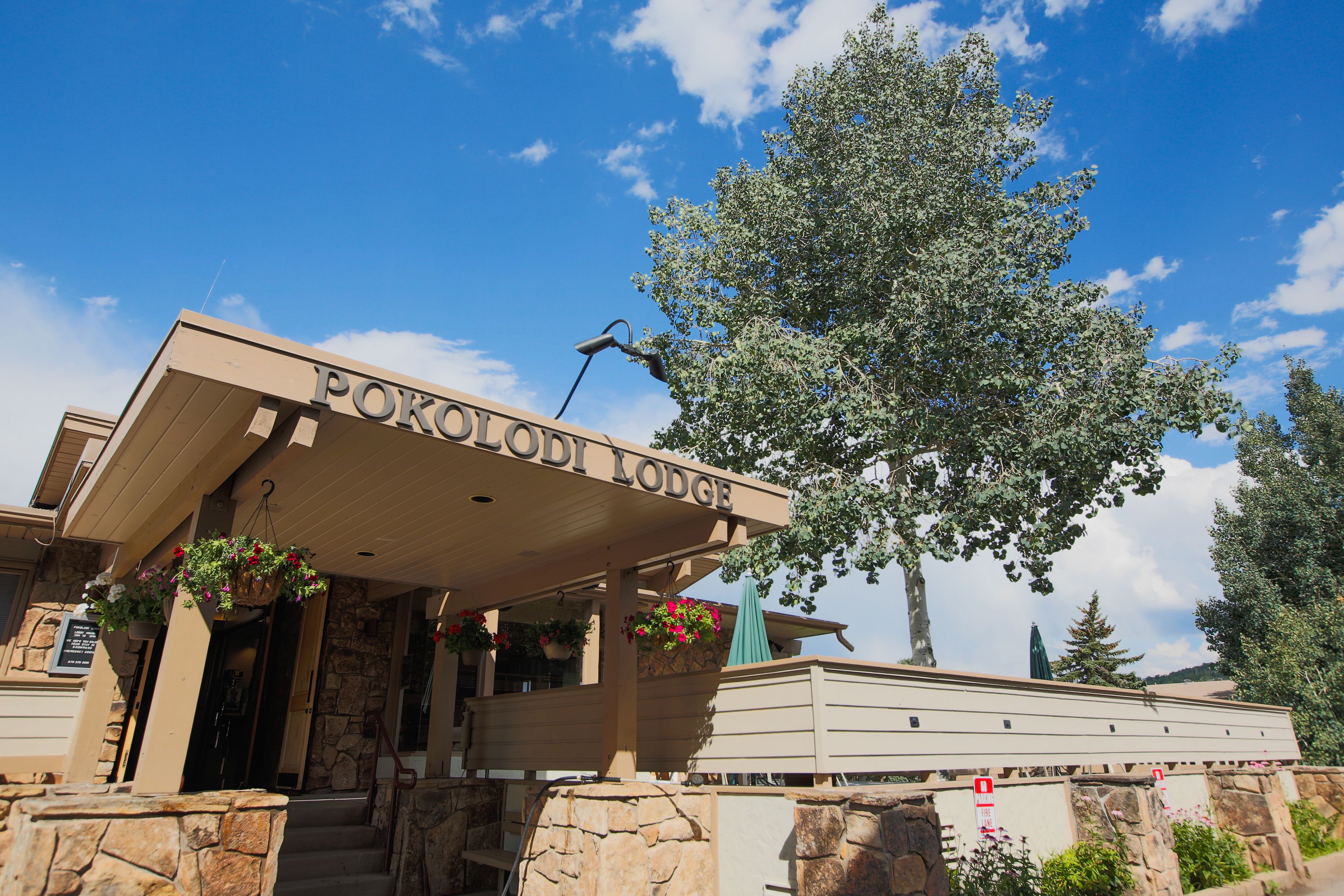 A building with a sign reading "POKOLODI LODGE" and a stone wall in front.