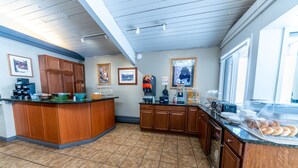 A kitchen with wooden cabinets, a coffee machine, and a breakfast bar with pastries. - Pokolodi Lodge (Snowmass Village)