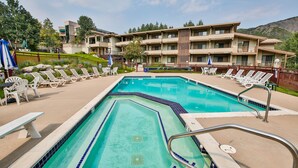 A swimming pool with lounge chairs and a building in the background. - Pokolodi Lodge (Snowmass Village)