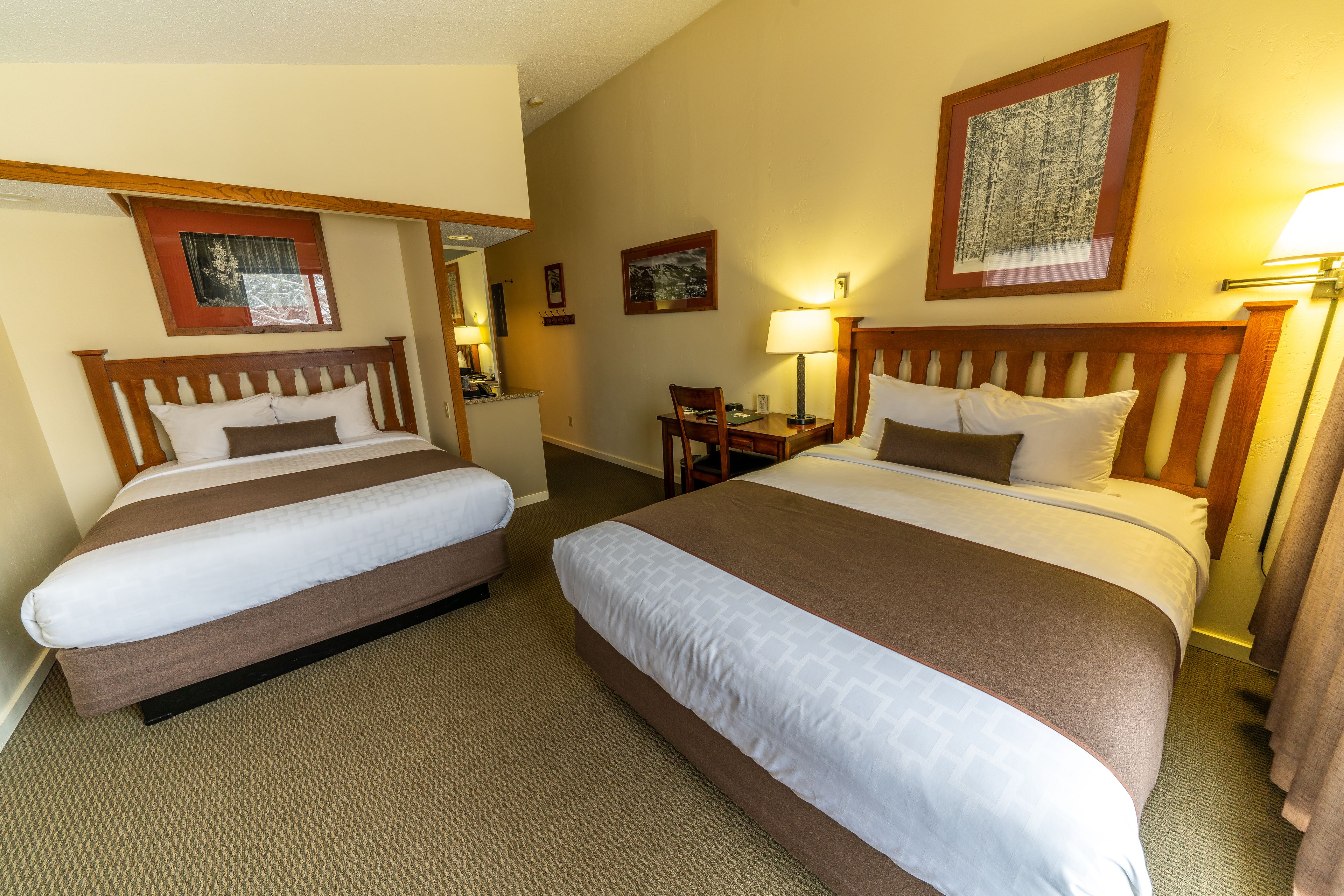 Ein Hotelzimmer mit zwei Betten, einem Schreibtisch und einem Stuhl.