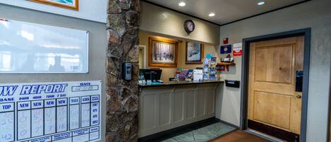 A reception area with a weather report board, a clock, and a wooden door.