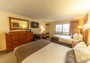 A hotel room with two beds, a dresser, a desk with a chair, a television, and a window with curtains. - Pokolodi Lodge (Snowmass Village)