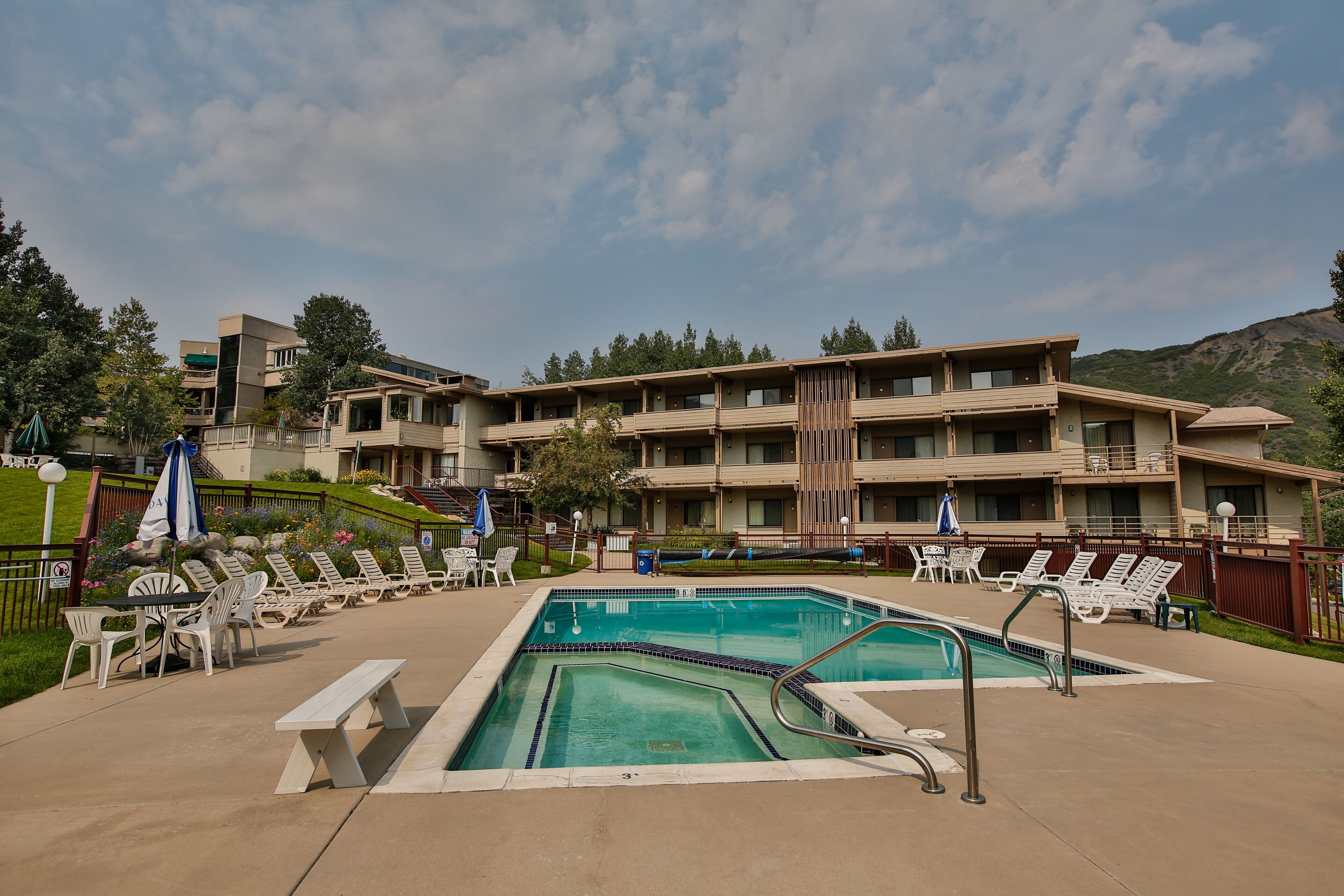 Un hotel con piscina, sillas de descanso y vistas a las montañas.