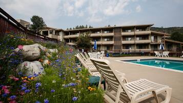A poolside area with lounge chairs, a swimming pool, and a building with multiple balconies.