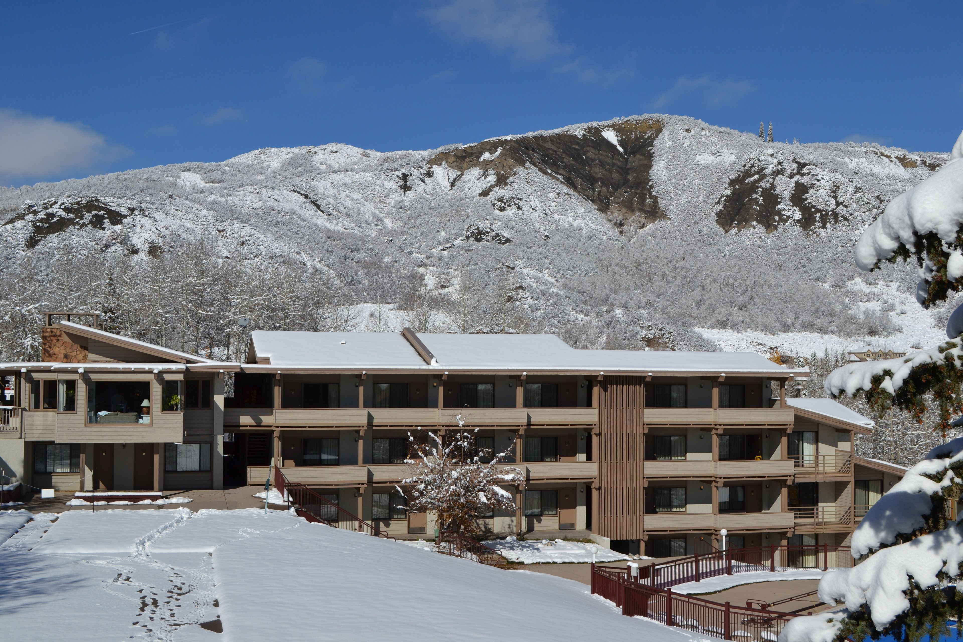 A multi-story hotel with a snow-covered landscape and mountains in the background.