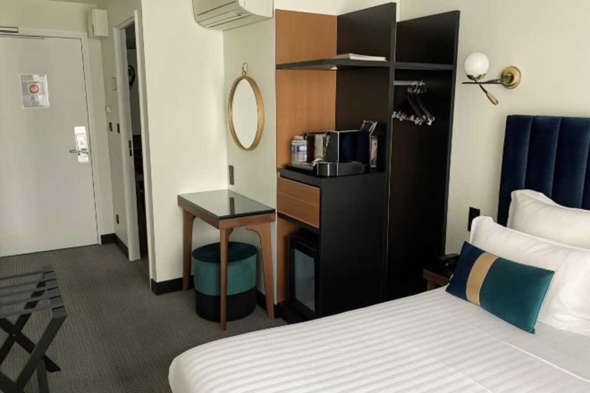 Una habitación de hotel con cama, escritorio, armario y una pequeña kitchenette.