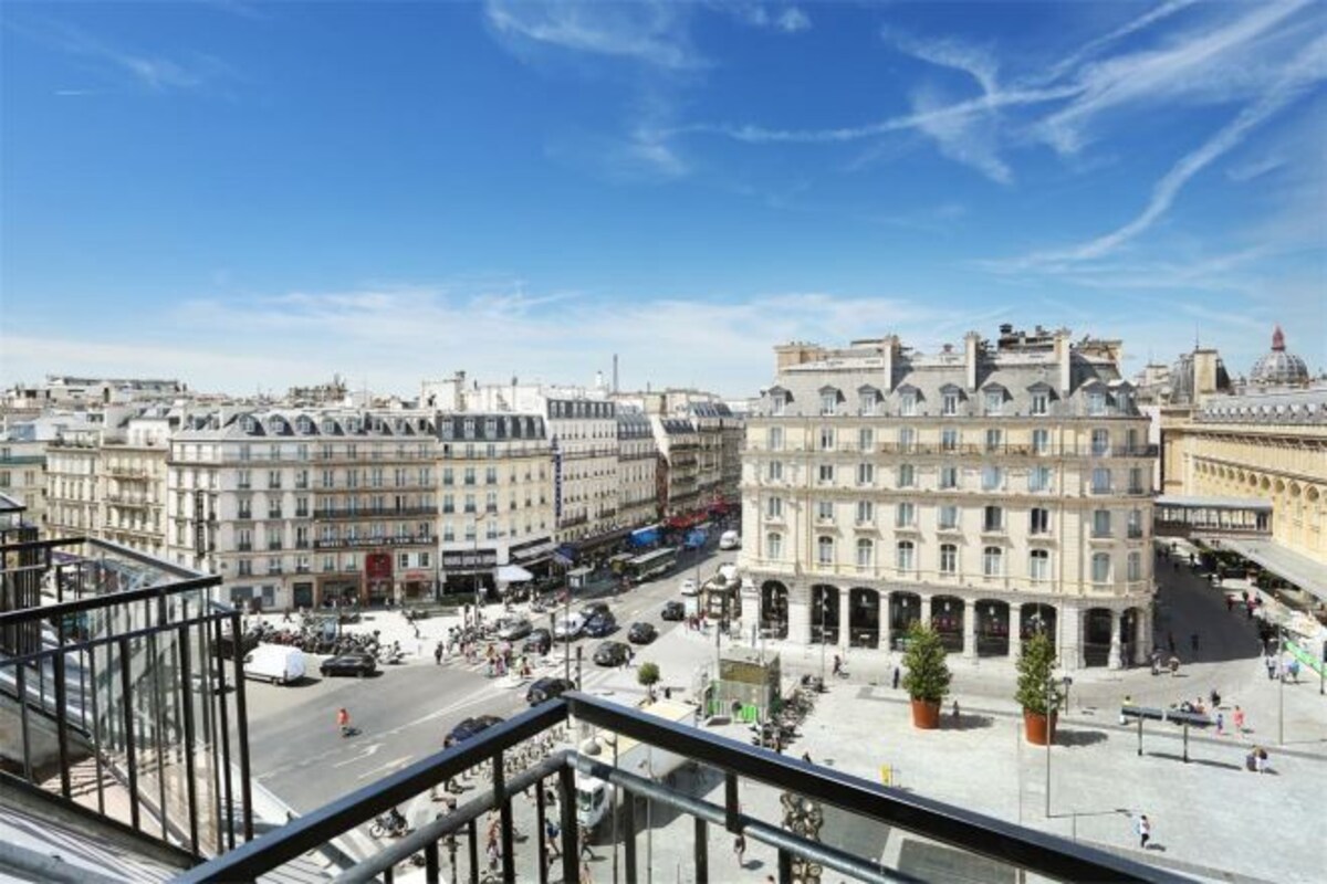 Un paisaje urbano con edificios históricos, una calle concurrida y cielo despejado.