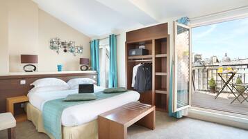 Une chambre d’hôtel avec un lit, un bureau, une armoire et un balcon donnant sur la ville.